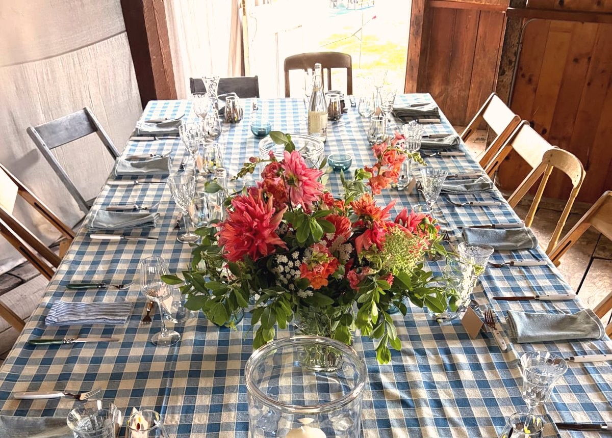 A long table in blue gingham with dahlias, glass hurricane and blue votives